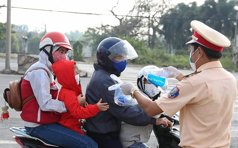 Lực lược CSGT Đồng Nai phát khẩu trang, nước uống, khăn lạnh cho người dân trên quốc lộ 51.